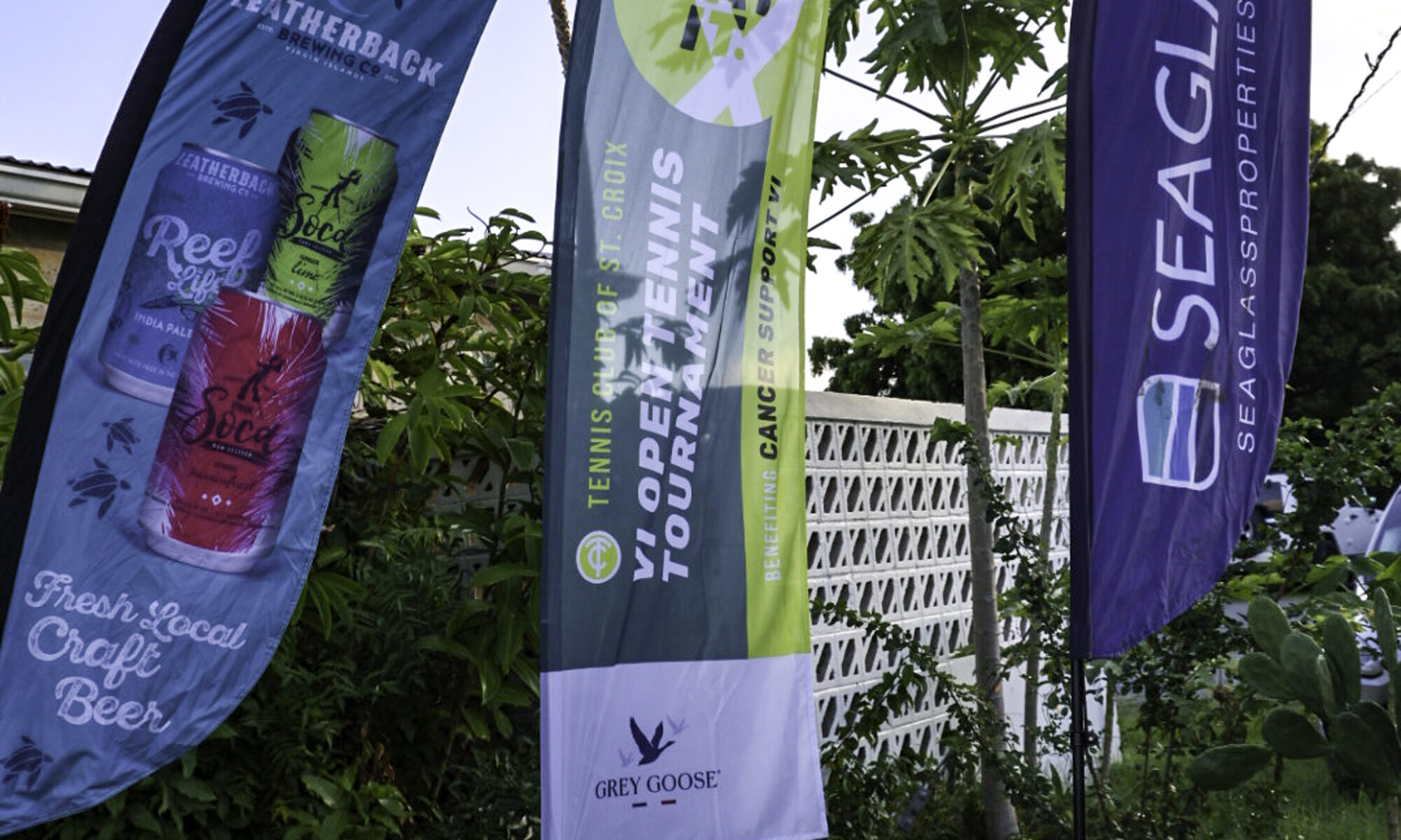 Sponsor flags for the Just Beat It Tennis Tournament, including banners for Leatherback Brewing, Sea Glass Properties, and Cancer Support VI.