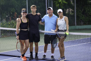 Finalist players of the A Division standing at the tennis net smiling after the match.