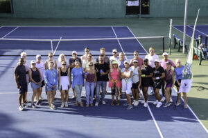 Large group photo of Just Beat It Tennis Tournament participants on the court.