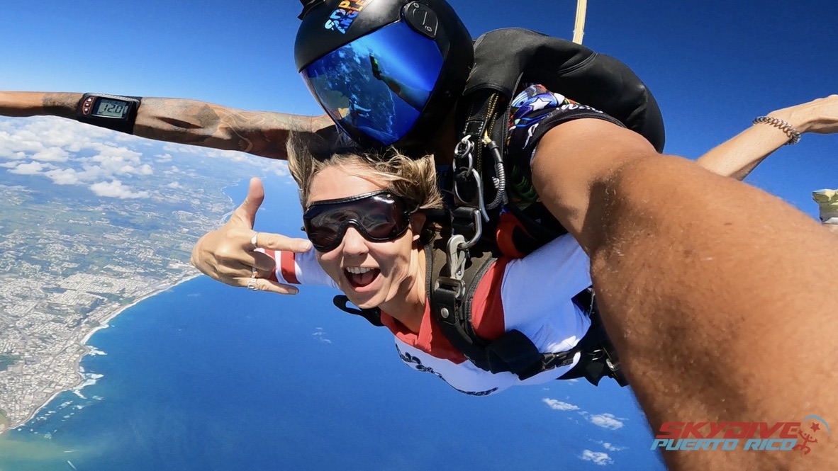 Kelsey Fischer skydiving tandem over Puerto Rico with ocean and coastline in the background