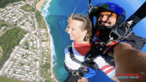 Kelsey Fischer under parachute with instructor nearing beach landing