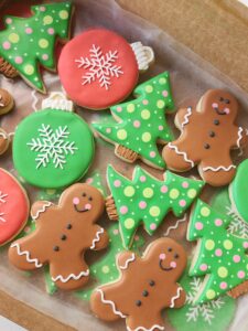 Decorated Christmas sugar cookies including gingerbread men, Christmas trees, and ornament shapes with bright icing designs.